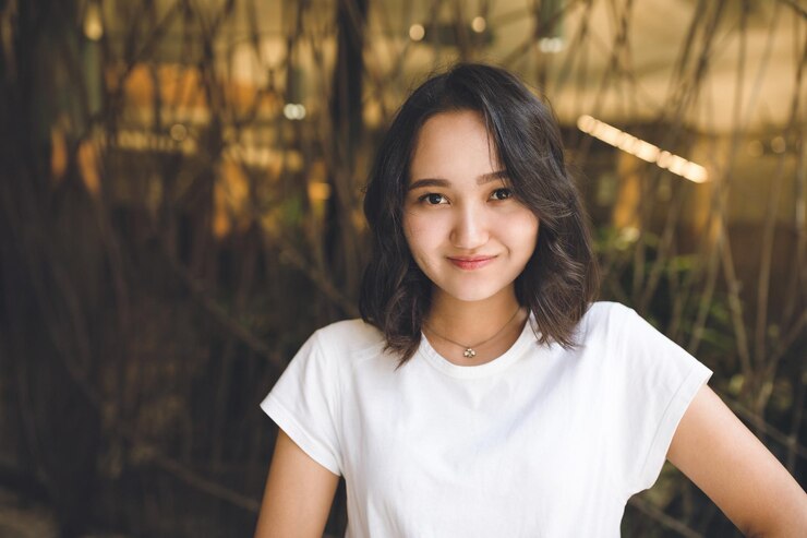 Photo 白いtシャツを着た陽気で楽観的なアジアの女の子がカメラのストリートポートレートを見て微笑んでいる