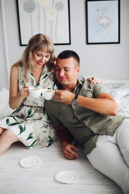 Cheerful pair sitting at home and drinking coffee together