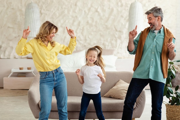 Фото Веселые родители и маленькая дочь танцуют, развлекаясь дома