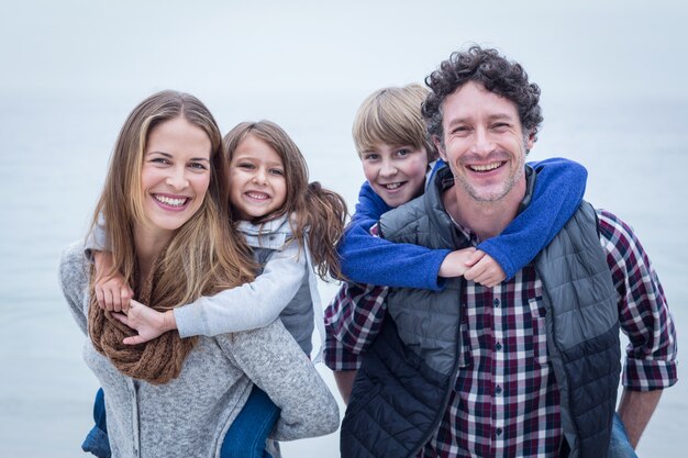 Cheerful parents carrying children at beach