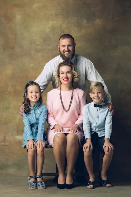 Cheerful parents and kids in official styled attire on dark vintage wall