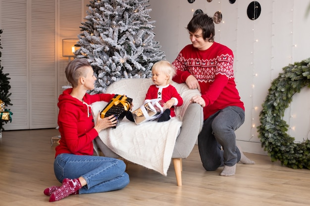 Cheerful parents and their little son exchanging gifts. Merry Christmas and Happy Holidays