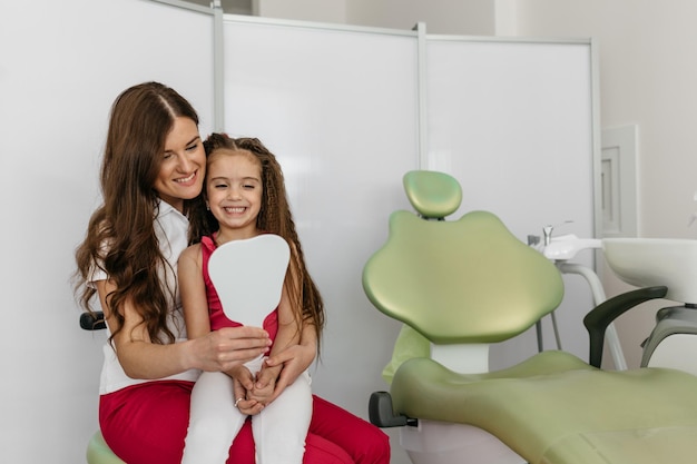 Cheerful pediatric dentist with a smiling young patient in dental clinic