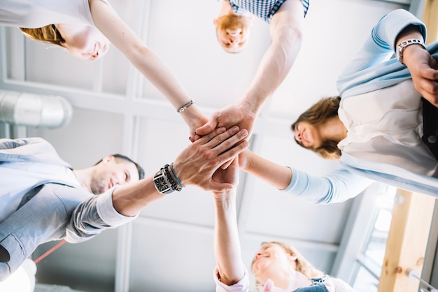 Cheerful people holding hands together in office