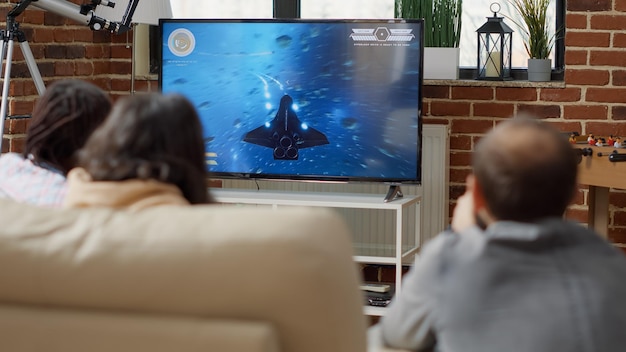 Cheerful people playing shooting video games on television, having fun together in living room. Group of friends enjoying online cyberspace competition for entertainment. Tripod shot.