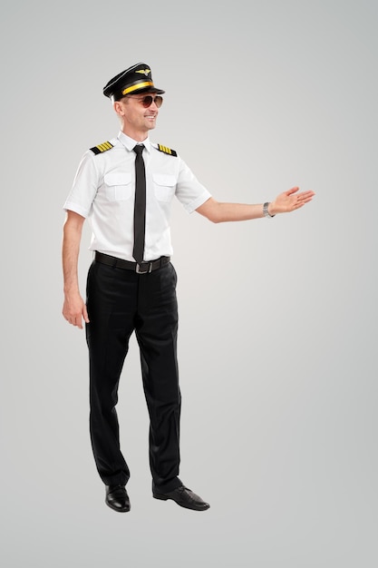 Cheerful pilot pointing aside in studio