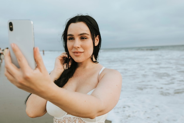 Cheerful plus size woman taking a selfie at the beach