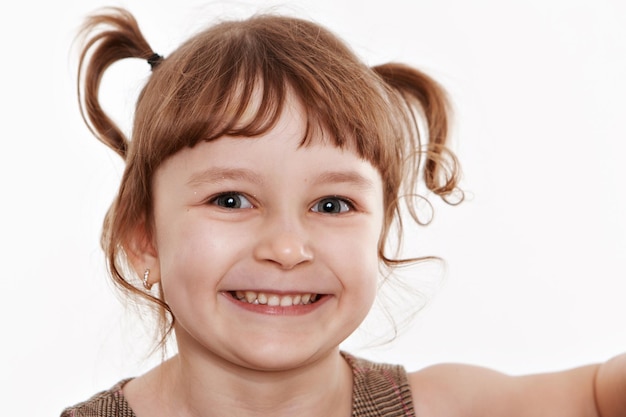 写真 ストライプのtシャツを着た2つのポニーの尾を持つ陽気なポジティブな愛らしい小さな子供は、両親のコピースペースから新しいおもちゃを受け取って喜んでいる楽しい感情を表現しています