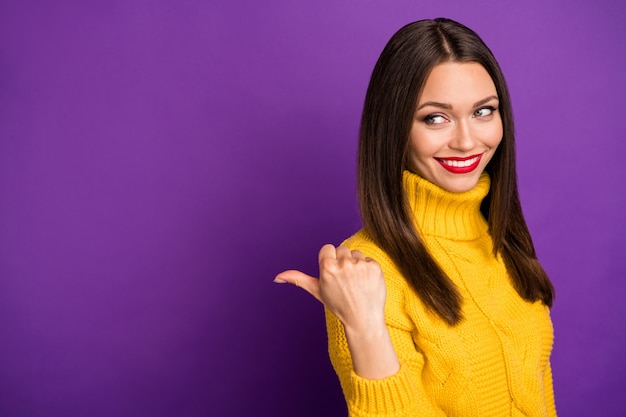 cheerful positive charming girl pointing with her thumb into empty space behind her back smile toothy .