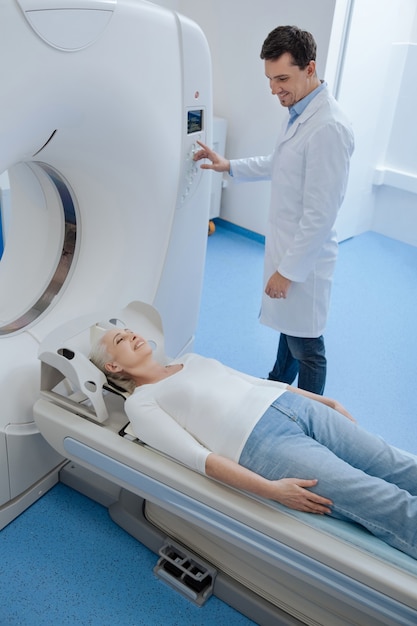 Cheerful positive senior woman lying on the examination table and smiling while undergoing medical examination