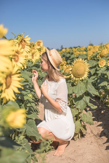 Cheerful positive young woman posing on camera among field of sunflowers Happy girl