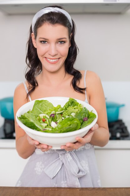 Cheerful pretty brunette showing healthy salad