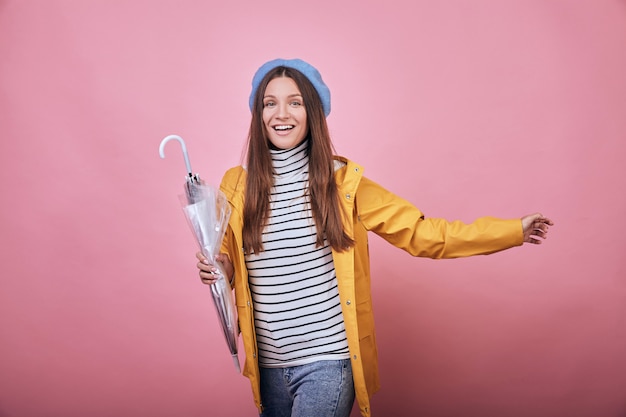 Cheerful pretty girl in yellow rain jacket with closed umbrella is runing