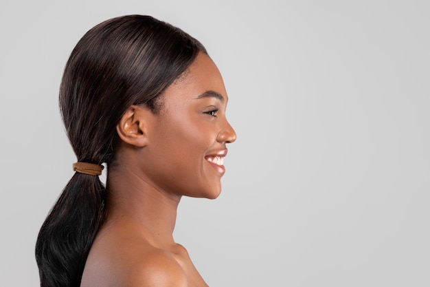 Cheerful pretty millennial african american lady with perfect skin and shiny hair isolated on gray