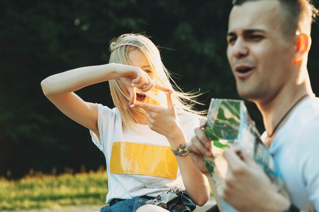 Cheerful pretty woman gesturing frame and looking at boyfriend in nature