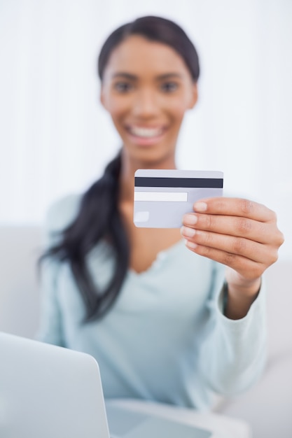 Cheerful pretty woman using her laptop to buy online