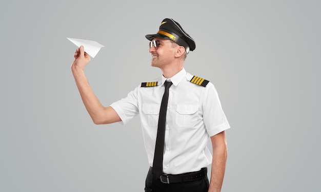 Cheerful professional pilot with paper plane