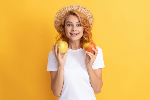 Cheerful redhead woman in straw hat hold apple, summer.