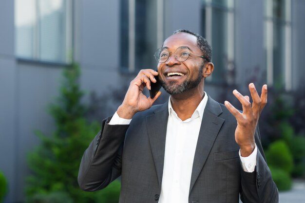 Cheerful and satisfied african american boss outside office building smiling and talking to