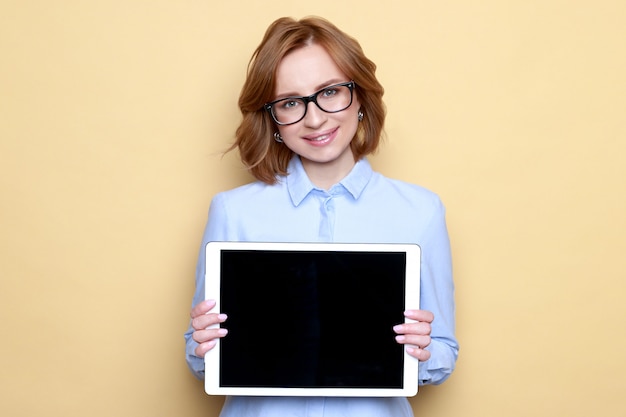 Cheerful satisfied smiling businesswoman showing black empty screen with copy space on digital tablet