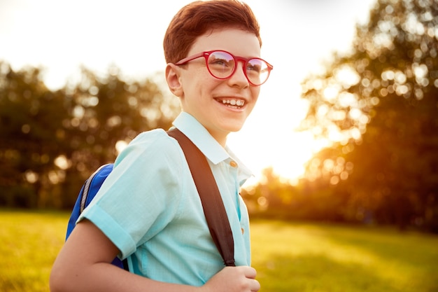 Cheerful schoolboy in park in evening