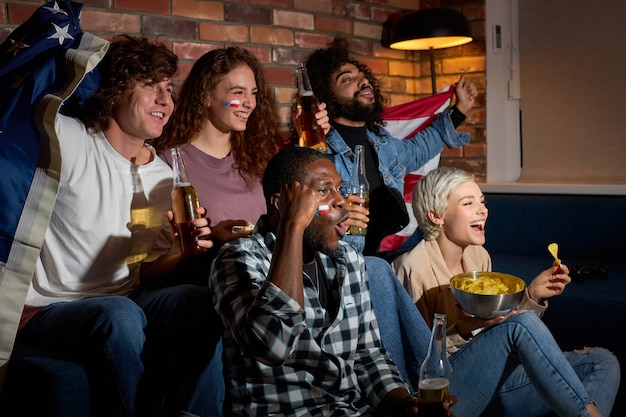 Photo cheerful screaming yelling students friends fans having day-off resting eating popcorn and drinking beer, celebrating goal or win of their favourite team