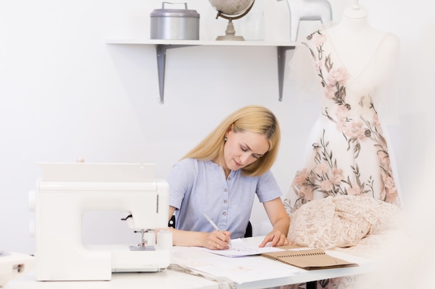 Cheerful seamstress sitting near sewing tools