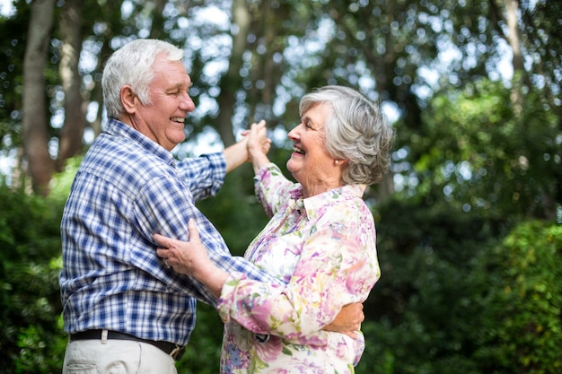 Cheerful senior couple dancing against trees
