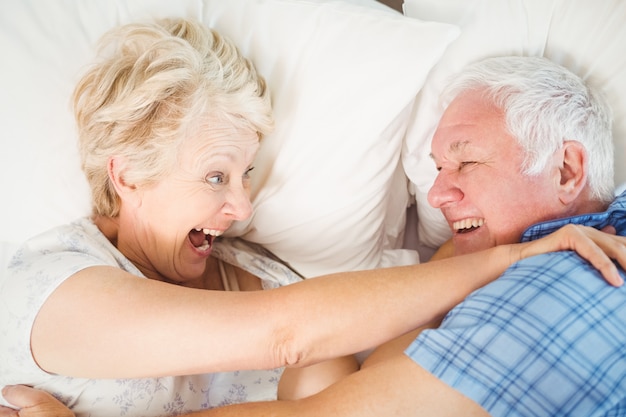 cheerful senior couple enjoying on bed