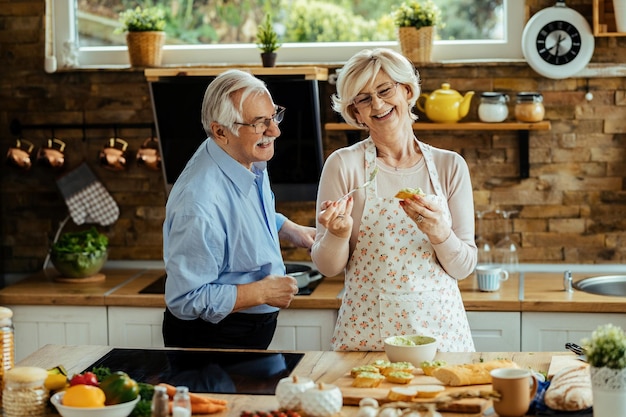 Cheerful senior couple having fun while cooking together in the kitchen.