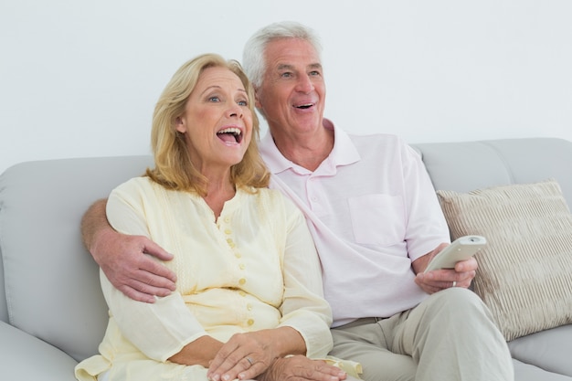 Cheerful senior couple with remote control at home