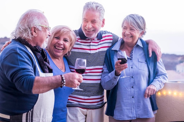 Cheerful senior friends standing at balcony during party