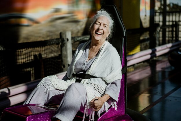 遊園地のバンパーカーで陽気な年配の女性