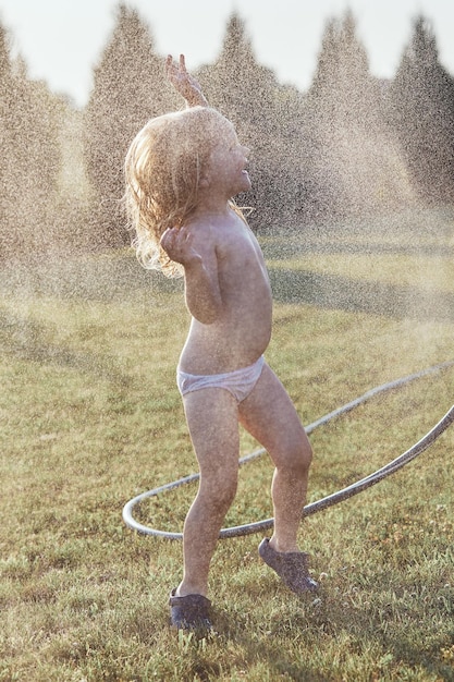 写真 陽気なシャツのない女の子が庭で楽しんでいます