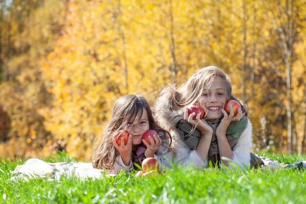 Фото Веселые сестры с красными яблоками на пикнике