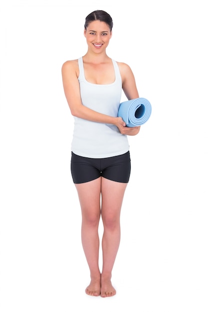 Cheerful slender model holding her rolled up mat