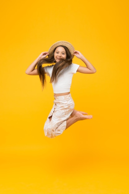 Cheerful small girl summer outfit jumping childhood happiness concept