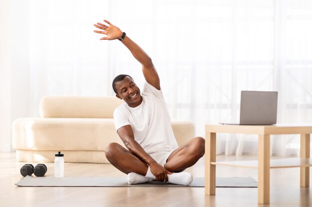 Cheerful smiling black guy training in living room