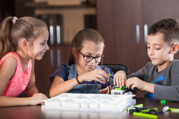 Cheerful smiling children are building a constructor.