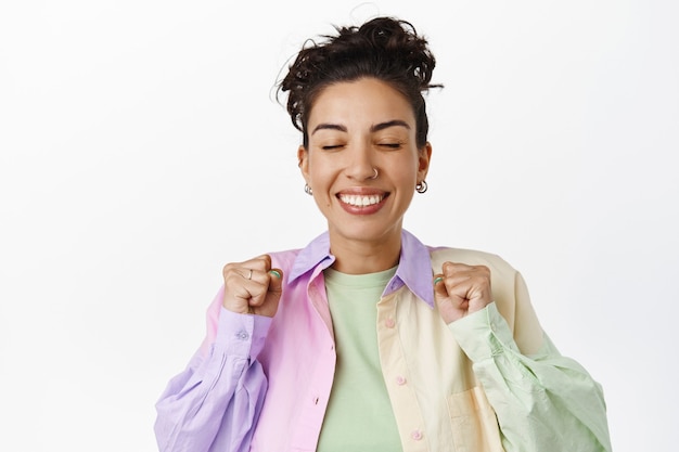 Cheerful smiling girl feeling rejoice and satisfaction of winning, celebrating success, achieve goal, jumping from joy on white