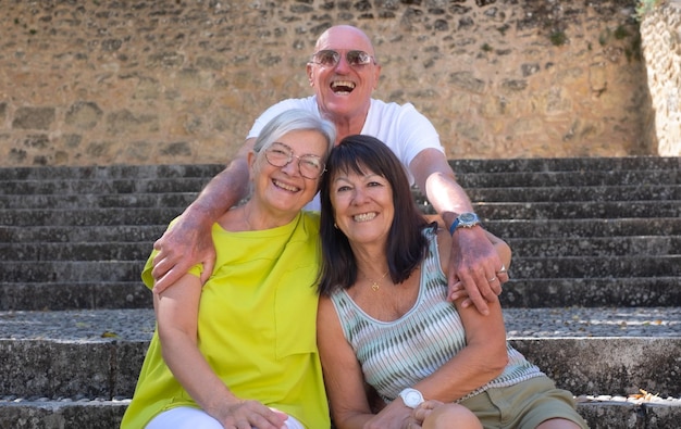 Cheerful smiling group of senior traveler people sitting on staircases posing for a souvenir photo