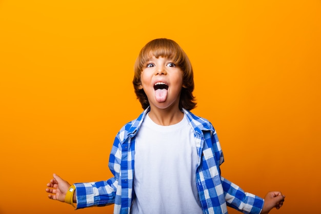 Cheerful smiling little boy jumping and having fun at the yellow wall. School concept.