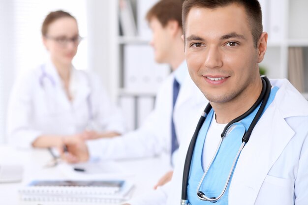 Cheerful smiling male doctor with medical staff at the hospital