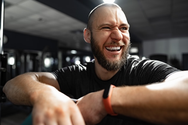 Cheerful smiling man bodybuilder standing in a gym