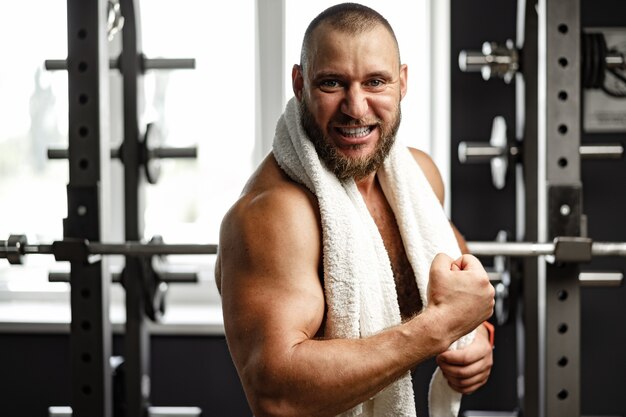 Foto allegro uomo sorridente bodybuilder in piedi in una palestra