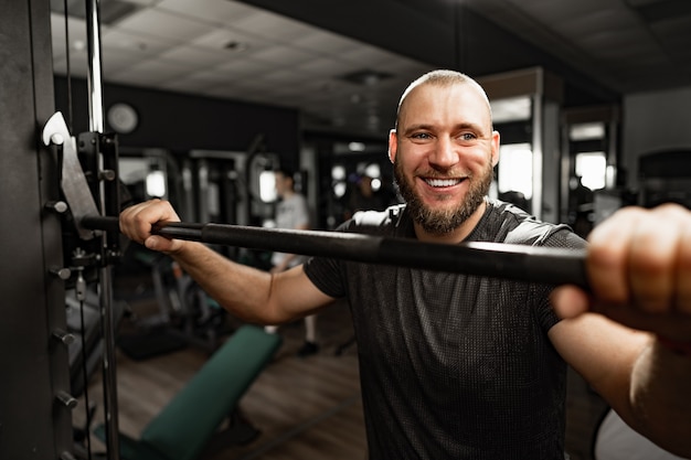 Cheerful smiling man bodybuilder standing in a gym