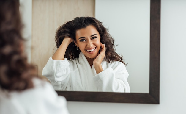 Foto una donna allegra e sorridente che si guarda nello specchio.