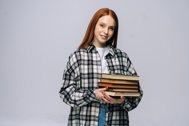 Фото Веселая улыбающаяся студентка колледжа молодой женщины держит книгу и смотрит в камеру