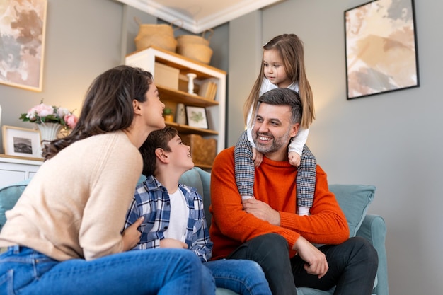 Cheerful son and daughter sitting with parents playing at home Playful little boy and girl enjoying spending time with parents at home