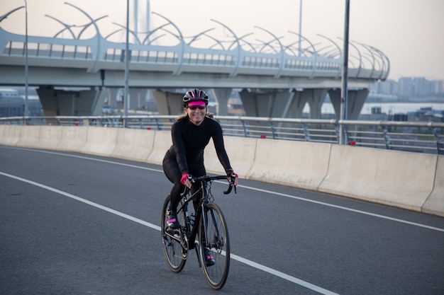 陽気なスポーツウーマンが自転車に乗る